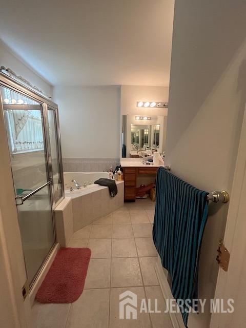 full bath with a stall shower, tile patterned flooring, a bath, and vanity