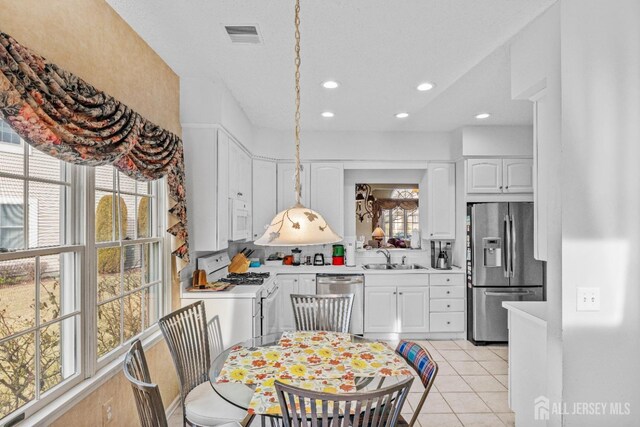 kitchen with sink, light tile patterned floors, appliances with stainless steel finishes, backsplash, and white cabinets