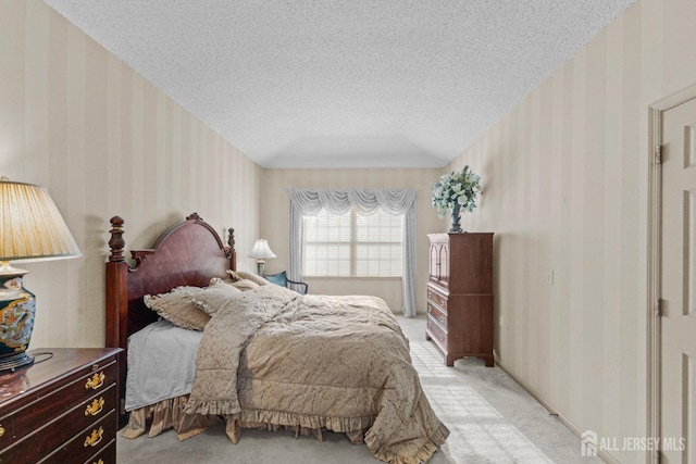 bedroom featuring light carpet, a textured ceiling, and wallpapered walls