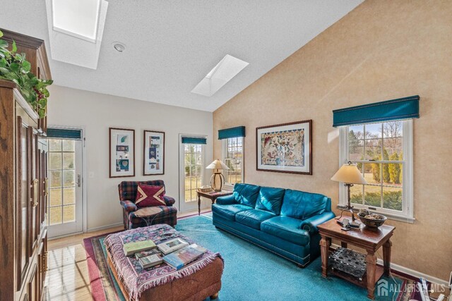 living area featuring vaulted ceiling with skylight and baseboards