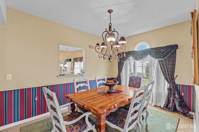 dining area featuring hardwood / wood-style floors, a notable chandelier, and a textured ceiling