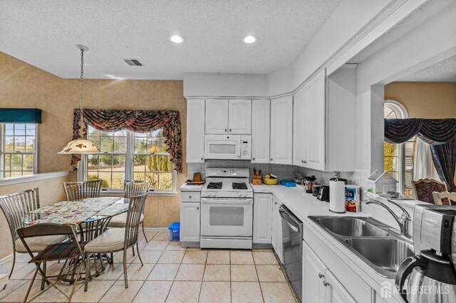 kitchen featuring sink, a textured ceiling, pendant lighting, white appliances, and white cabinets