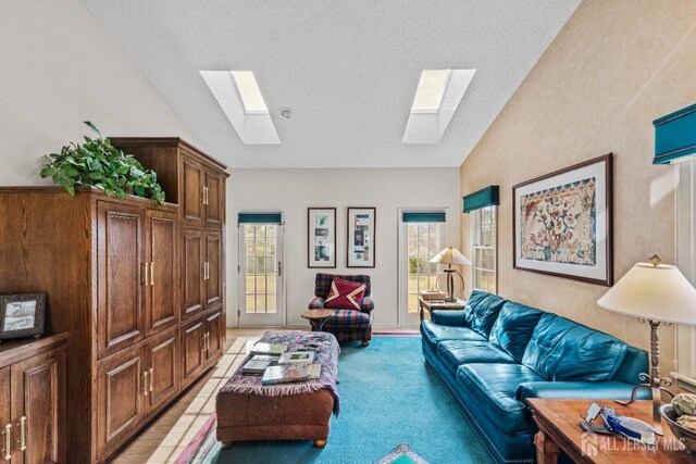 living area with light carpet, vaulted ceiling with skylight, and a textured ceiling