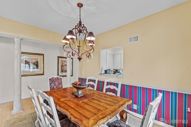 dining space featuring an inviting chandelier, light hardwood / wood-style flooring, and ornate columns