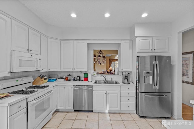 kitchen with stainless steel appliances, light countertops, a sink, and white cabinetry