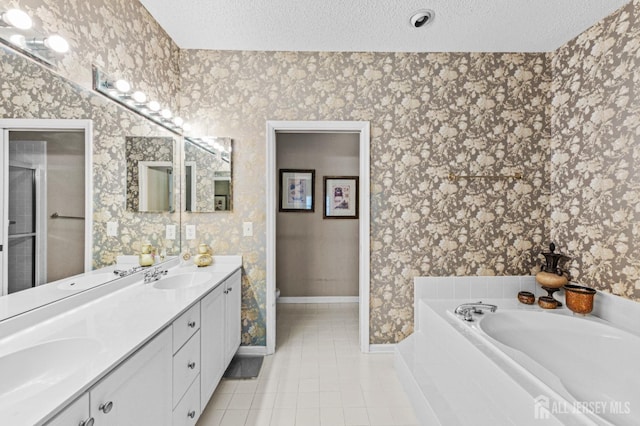 bathroom featuring vanity, a tub to relax in, tile patterned floors, and a textured ceiling