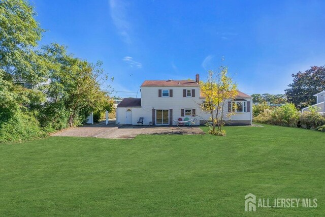 back of house with a patio area and a lawn