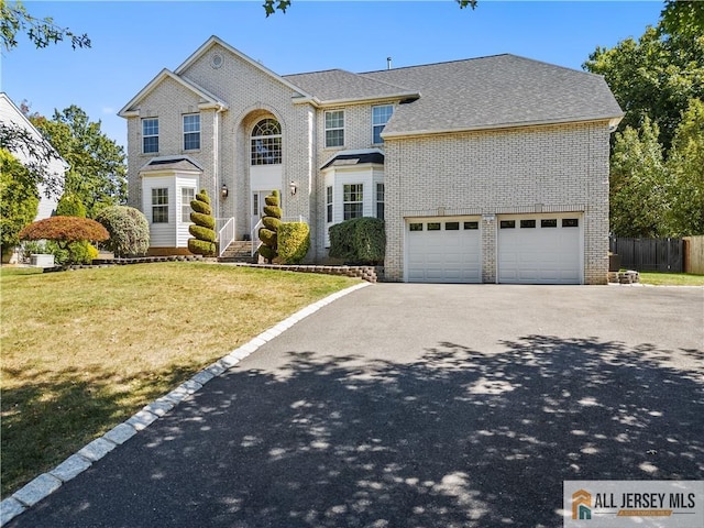 view of front of house with a garage, brick siding, driveway, and a front lawn