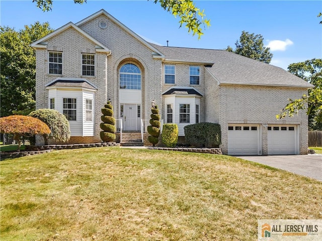 traditional-style home with driveway, brick siding, and a front yard