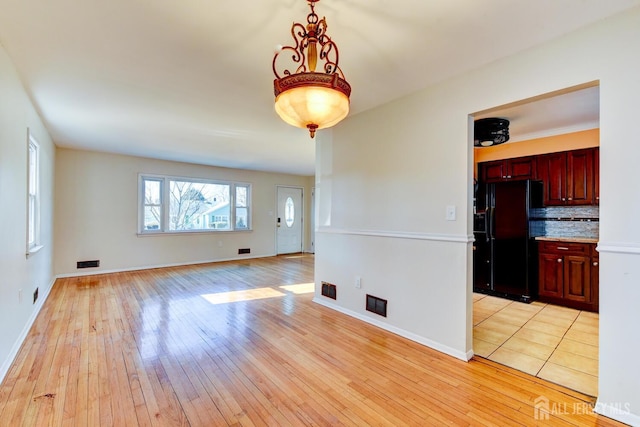 interior space with light wood finished floors, visible vents, and baseboards