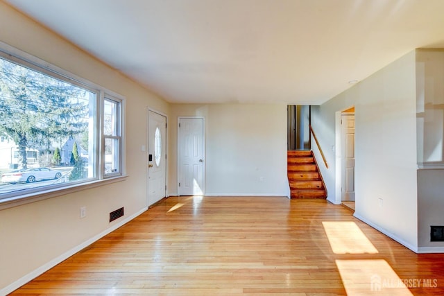 foyer featuring baseboards, light wood finished floors, and stairs