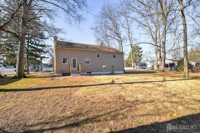 back of house featuring entry steps, cooling unit, and a lawn