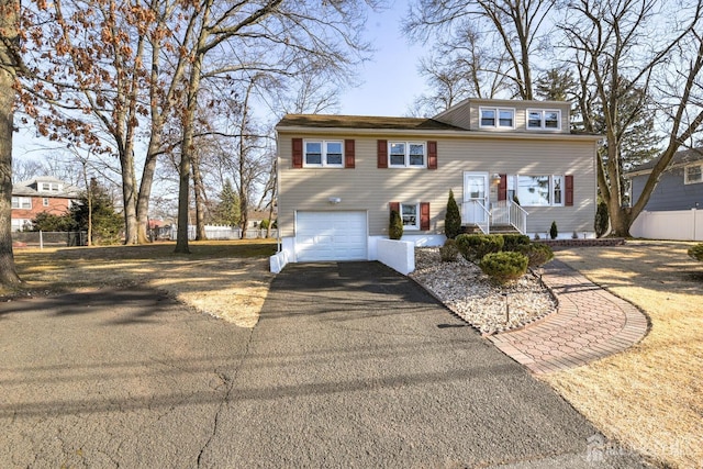 view of front of property featuring driveway, an attached garage, and fence