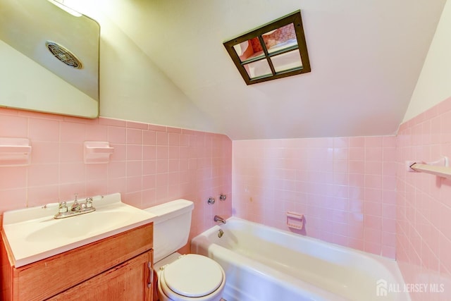 full bath featuring a tub to relax in, toilet, vaulted ceiling, vanity, and tile walls