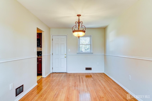 unfurnished dining area with light wood-type flooring, visible vents, and baseboards