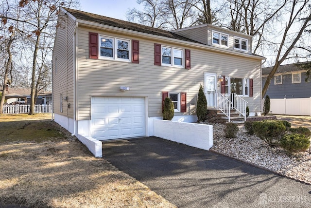 view of front of home with a garage, fence, and aphalt driveway