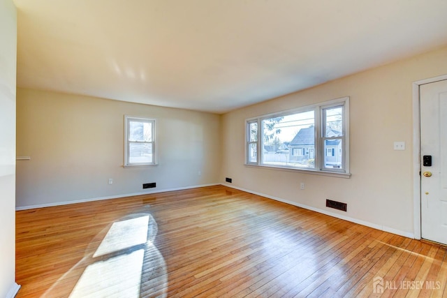 unfurnished living room featuring light wood-style flooring, visible vents, and baseboards