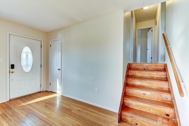 foyer entrance featuring stairs, light wood-type flooring, and baseboards