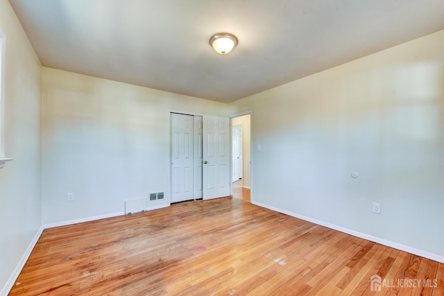 unfurnished room with baseboards, visible vents, and wood finished floors