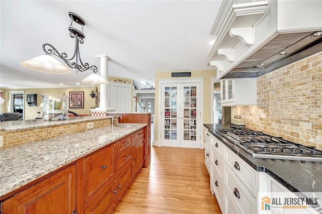 35 Parkview Rd, Cranbury, NJ 08512 - kitchen with stainless steel gas stovetop, custom range hood, french doors, tasteful backsplash, and light stone counters