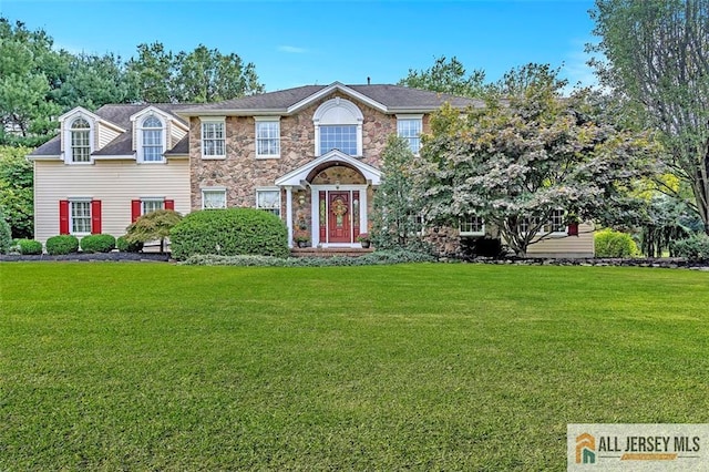 colonial house with stone siding and a front yard