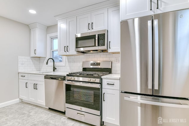 kitchen featuring stainless steel appliances, a sink, white cabinetry, and light stone countertops