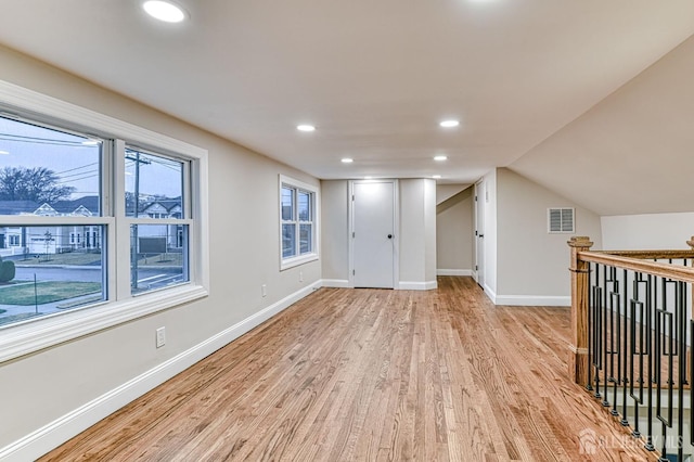 interior space featuring visible vents, baseboards, light wood-style flooring, vaulted ceiling, and recessed lighting