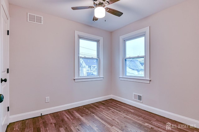 spare room featuring light wood-style floors, a ceiling fan, visible vents, and baseboards