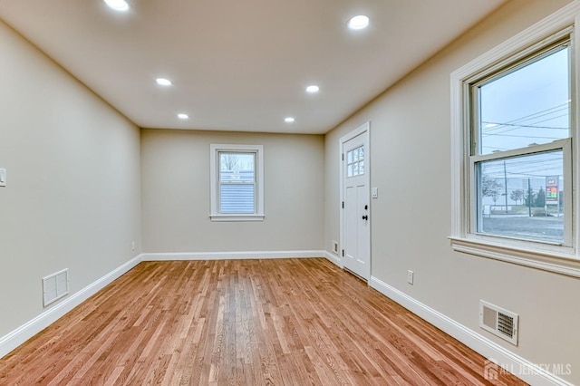 spare room featuring light wood finished floors, baseboards, visible vents, and recessed lighting