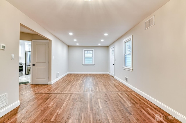 unfurnished room featuring baseboards, visible vents, and light wood-style floors