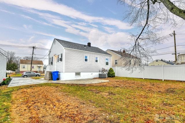 rear view of property with a yard, a chimney, fence, and a patio