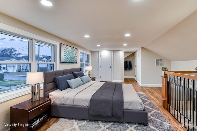 bedroom featuring light wood finished floors, baseboards, visible vents, vaulted ceiling, and recessed lighting