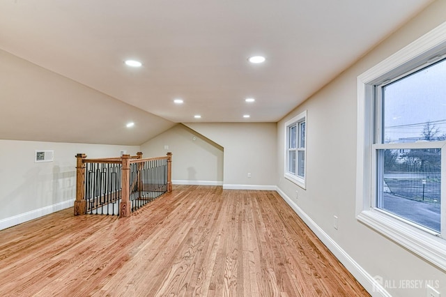 additional living space featuring light wood finished floors, baseboards, visible vents, lofted ceiling, and recessed lighting