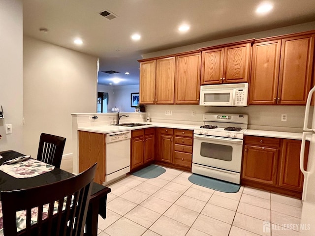 kitchen featuring recessed lighting, a sink, brown cabinets, and white appliances