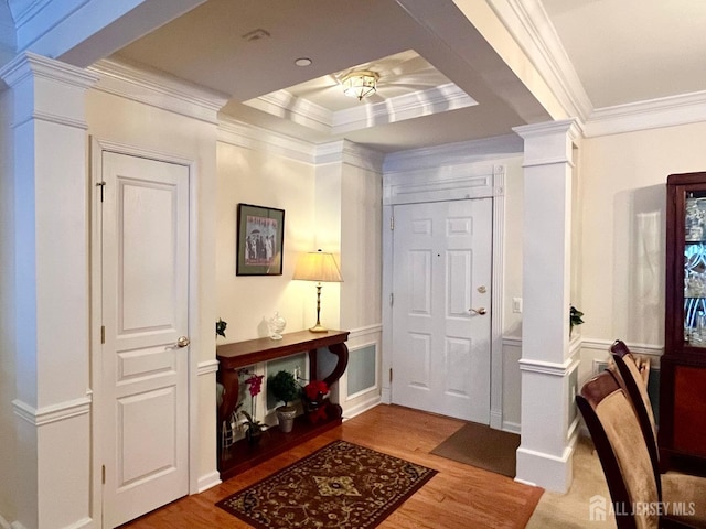 entrance foyer featuring ornate columns, ornamental molding, wood finished floors, and a decorative wall