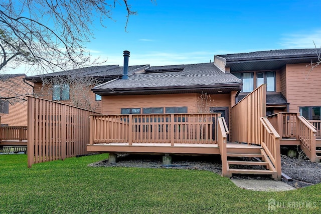 rear view of property featuring a wooden deck, a yard, and roof with shingles