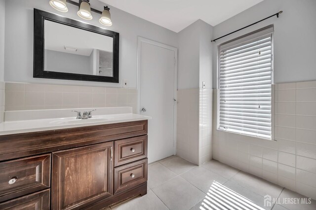 bathroom featuring tile patterned floors, a wainscoted wall, tile walls, and vanity