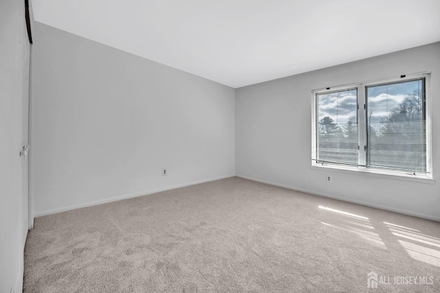 carpeted empty room featuring baseboards