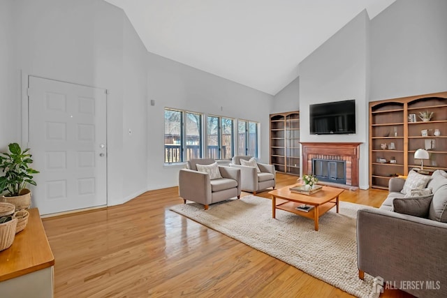 living area featuring a fireplace, light wood-style floors, and high vaulted ceiling