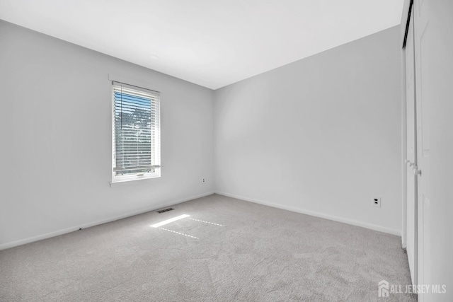 carpeted empty room with visible vents and baseboards