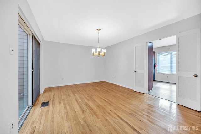 unfurnished room featuring visible vents, baseboards, a notable chandelier, and light wood finished floors