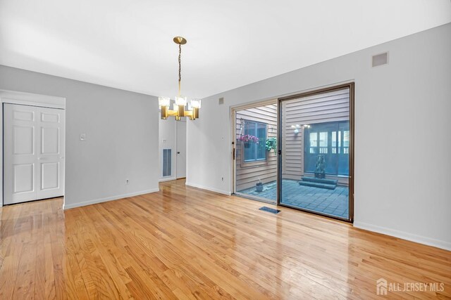 unfurnished room with visible vents, baseboards, an inviting chandelier, and light wood-style flooring