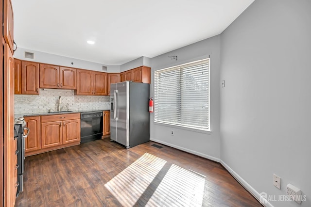 kitchen featuring visible vents, dark wood finished floors, a sink, appliances with stainless steel finishes, and backsplash