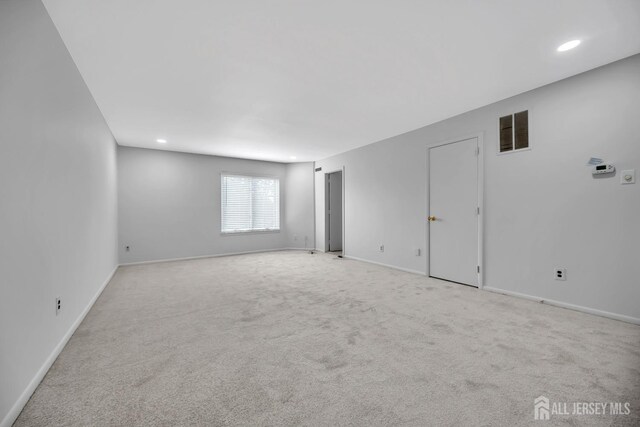 spare room with recessed lighting, baseboards, visible vents, and light carpet