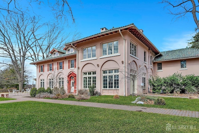 view of front of property with stucco siding, a chimney, and a front yard