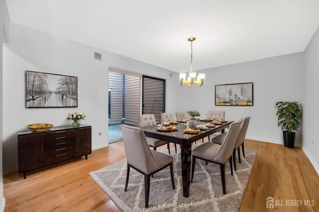 dining space with visible vents, a notable chandelier, baseboards, and light wood-type flooring