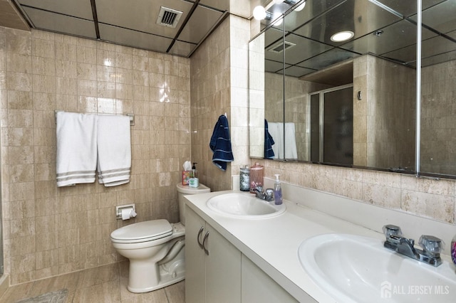 bathroom with a sink, tile walls, a shower stall, and double vanity