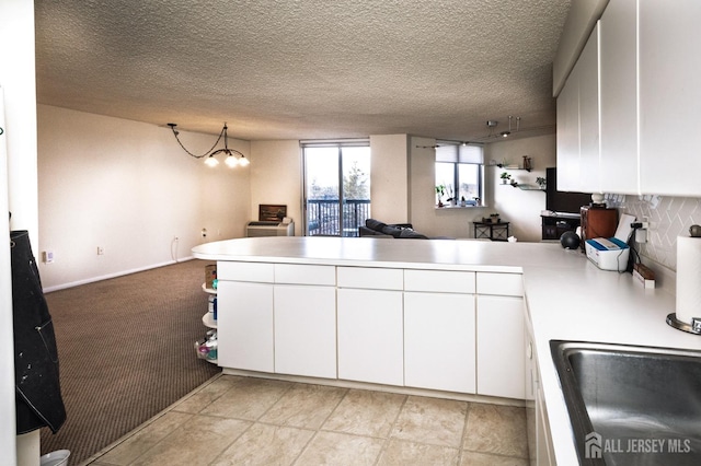 kitchen with open floor plan, light countertops, a peninsula, and white cabinets