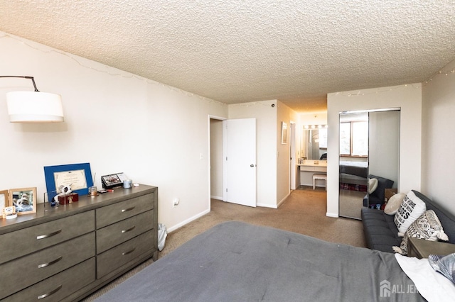 carpeted bedroom with a textured ceiling, connected bathroom, and baseboards