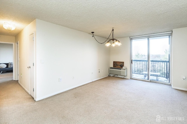 unfurnished room with light carpet, expansive windows, a textured ceiling, and a notable chandelier